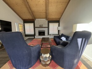 A living room with a brick fireplace, a sofa, two armchairs, and a coffee table.
