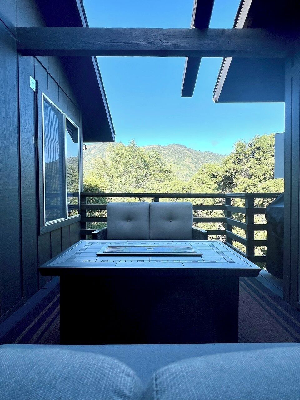 A balcony with a table and chairs, overlooking a mountainous landscape.