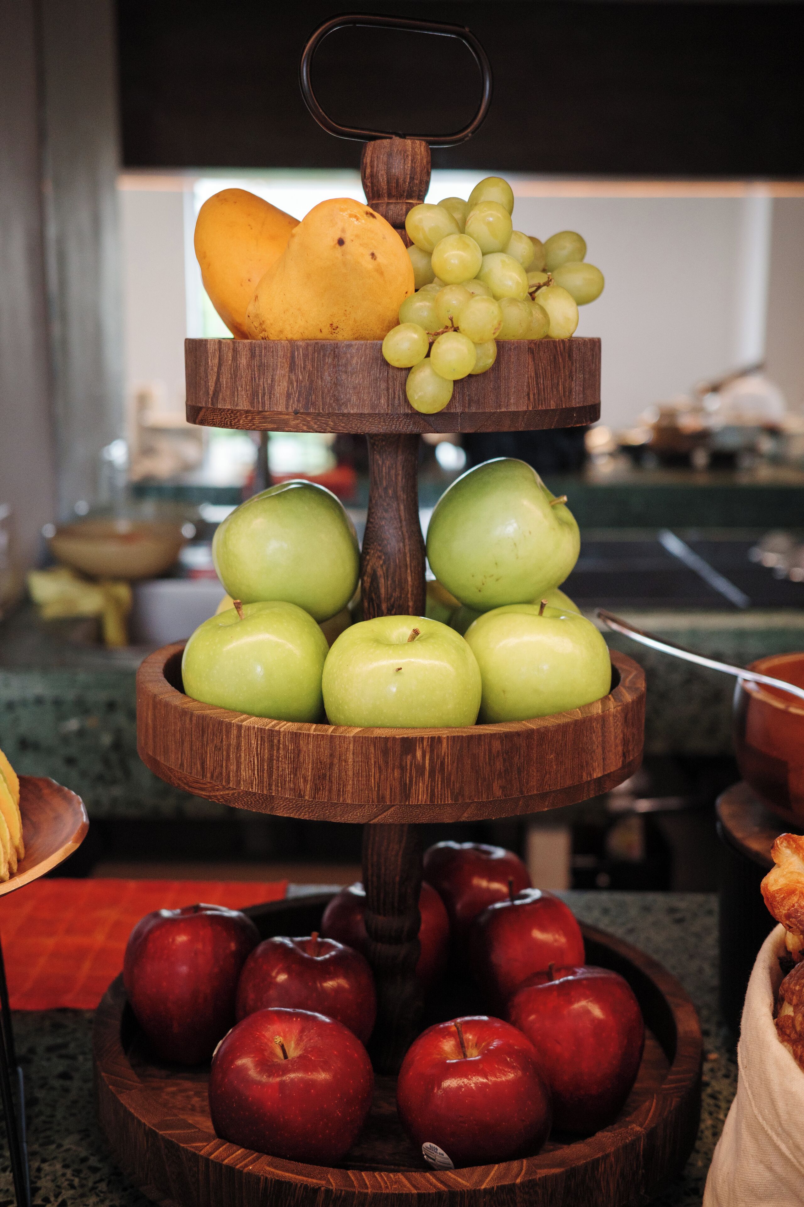 Een houten fruitkraam met meerdere lagen, met appels, druiven en peren.