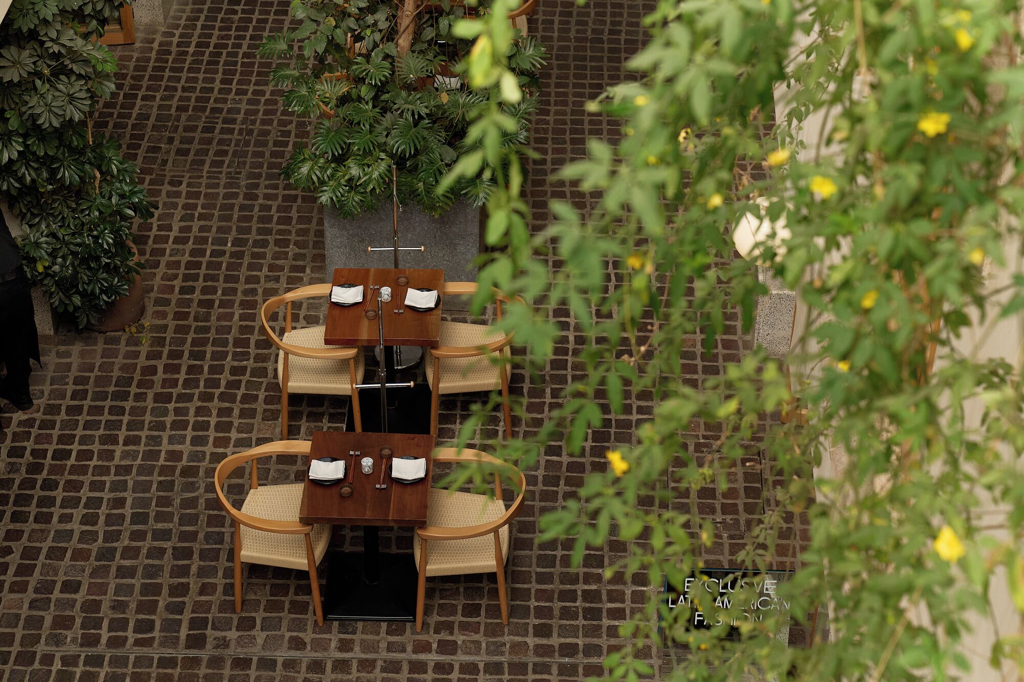 Een terras met tafels en stoelen, omringd door plantenpotten en een geplaveid terras.