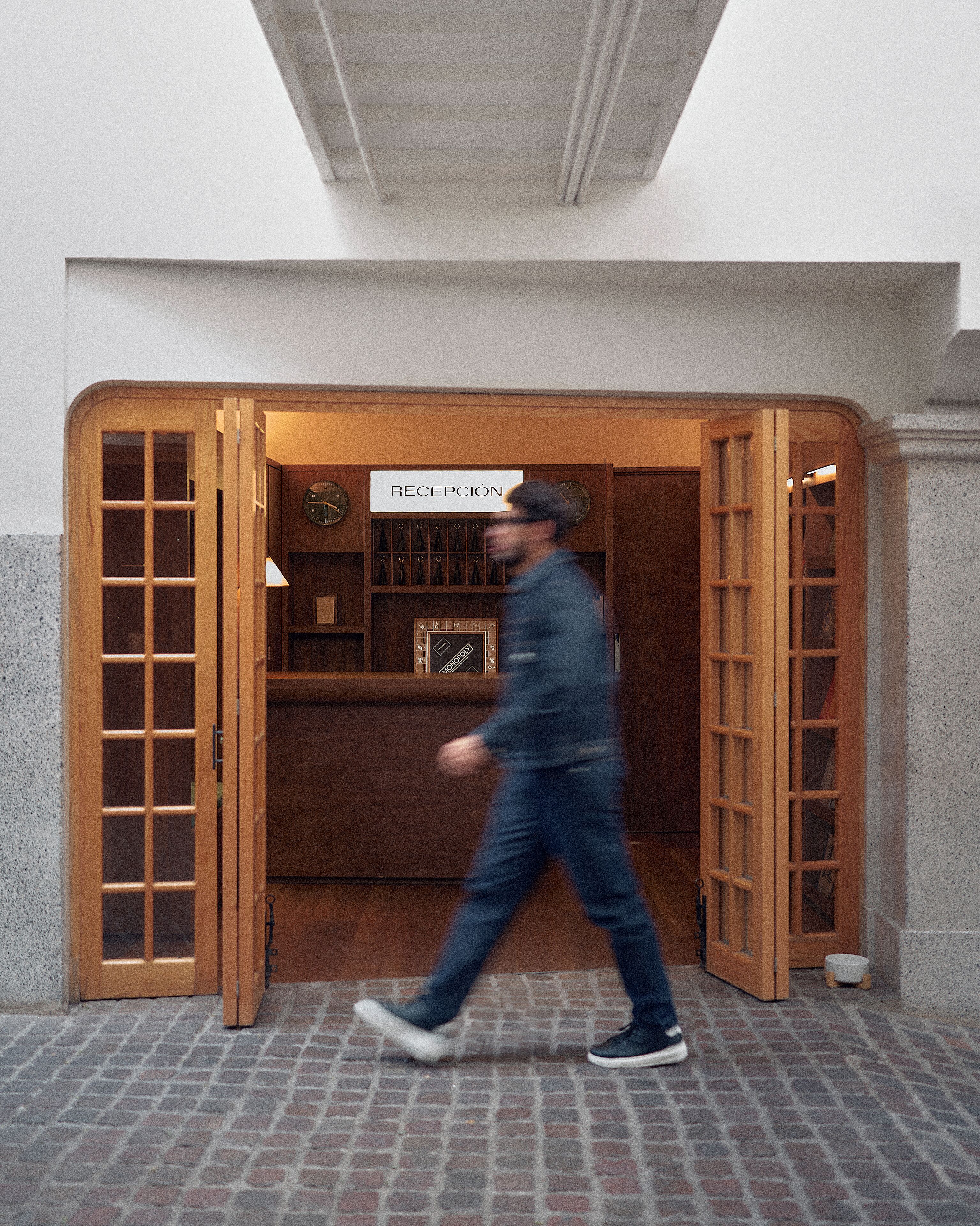 A wooden reception desk with a sign reading "RECEPCIÓN" and a clock above it.