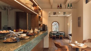 A breakfast bar with a variety of food items and a coffee station. There is a seating area with tables and chairs. - Hotel Parián (Mexico City)