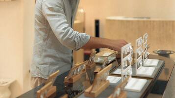 Une personne dispose des objets sur une table en verre dans un intérieur moderne agrémenté d’éléments en bois et où l’on peut voir une signalisation indiquant la sortie de secours.