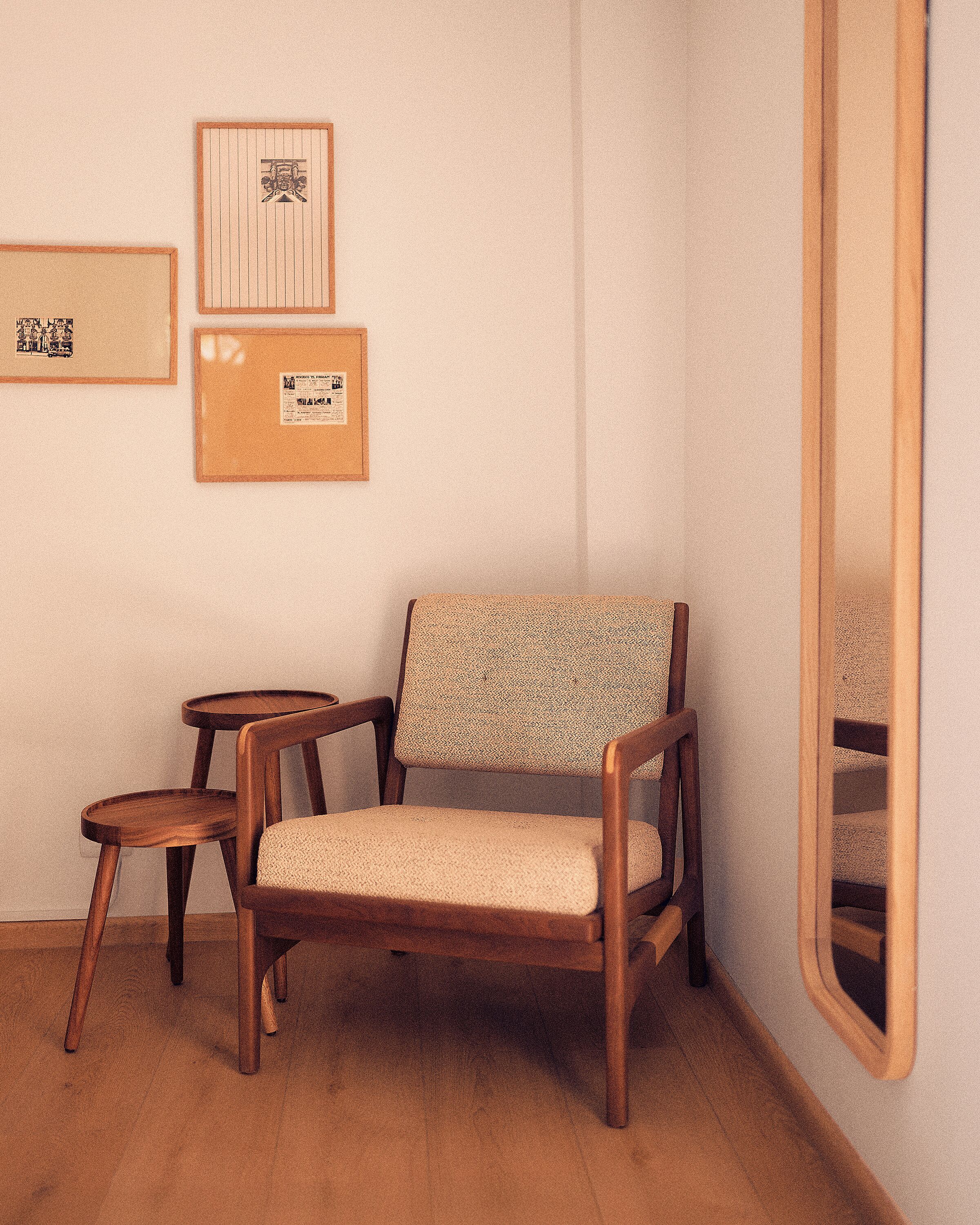 Una habitación con una silla de madera, una mesita redonda pequeña y dos objetos enmarcados en la pared.