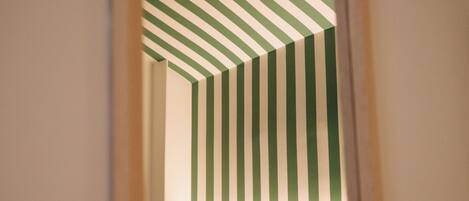 Habitación de hotel con techo a rayas, cabecera de madera y lámpara de noche.