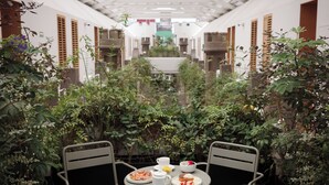 A courtyard with a table set for breakfast, surrounded by lush greenery and white walls. - Hotel Parián (Mexico City)