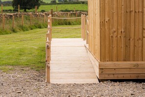 A wooden deck leading to a building with a simple, rustic design.