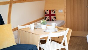 Una habitación acogedora con una mesa de madera preparada para comer, una cama con cubrecama azul y una bandera británica en la pared.