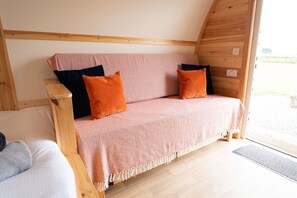 A cozy wooden interior with a sofa bed, pillows, and a wooden headboard.