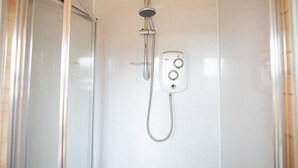 Een kleine, afgesloten douchecabine met een handdouche en bedieningspaneel.