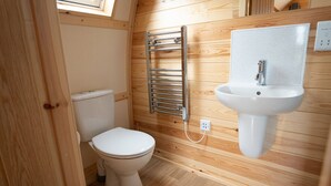 Une petite salle de bain avec des toilettes blanches, un porte-serviettes chromé et un lavabo blanc avec un pare-éclaboussures à motifs.