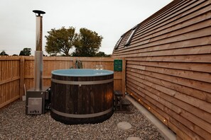 Un bain à remous avec un revêtement extérieur en bois, un réchauffeur en métal et une clôture en bois.