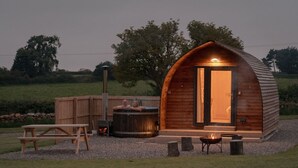 Une cabane en bois avec une grande porte, un bain à remous et une table de pique-nique.