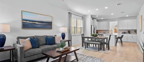 A modern living room with a sofa, coffee table, and a painting on the wall.