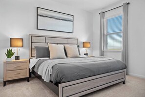 A modern bedroom with a bed, nightstands, a potted plant, and a large window with blinds. - Modern Retreat in Hutto (Hutto)