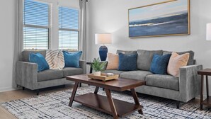 A living room with two grey sofas, a wooden coffee table, a lamp, and a framed landscape painting on the wall. - Modern Retreat in Hutto (Hutto)