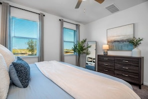 Un dormitorio con cama, cómoda, espejo y un cuadro en la pared.