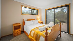 Een slaapkamer met een houten bed, een nachtkastje, een raam en een schuifdeur naar een balkon.