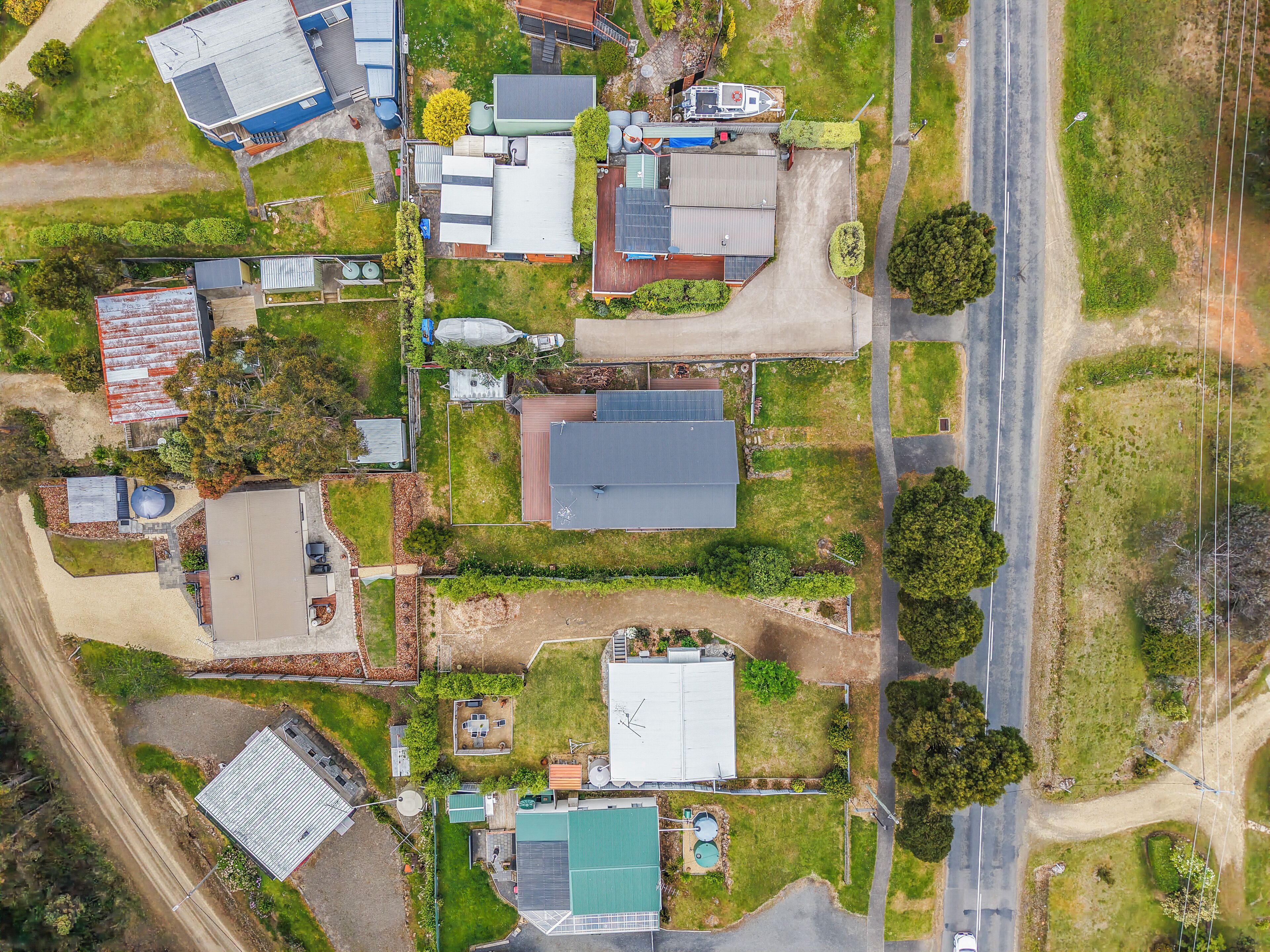 An aerial view of a residential area with multiple houses, a road, and a small parking area.