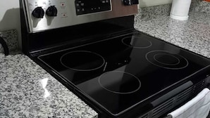 A black stovetop with four burners and a control panel with knobs and buttons.