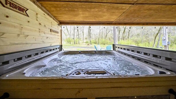 A hot tub under a wooden shelter with a view of trees. - Diamond in the Ruff -4bdrm Hot Tub / Firepit / Boat Parking Broken Bow Hochatown (Broken Bow)