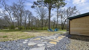A wooden cabin with a stone pathway leading to outdoor seating. - Diamond in the Ruff -4bdrm Hot Tub / Firepit / Boat Parking Broken Bow Hochatown (Broken Bow)