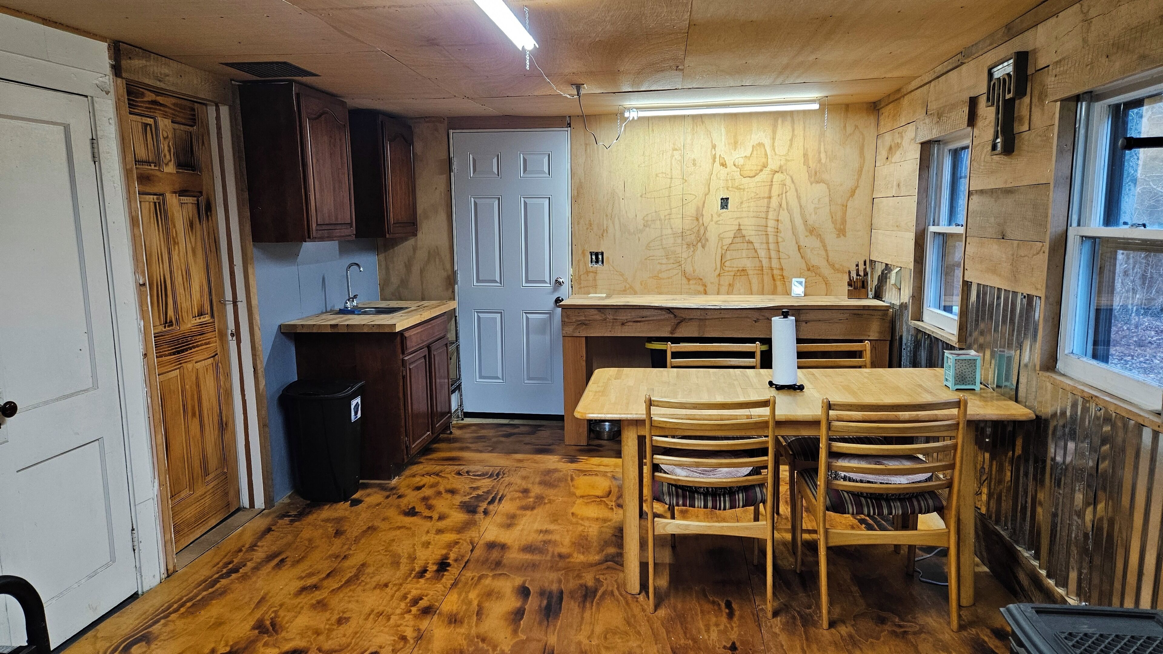 A compact kitchen with wooden cabinets, a sink, and a dining table with chairs.