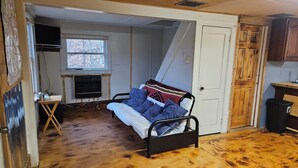 A bedroom with a bed, a window, a small table, and a door. - 1-bedroom cabin in Redfield (Redfield)