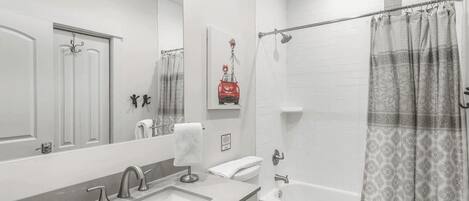 A modern bathroom with a large mirror, a sink, a toilet, and a shower.