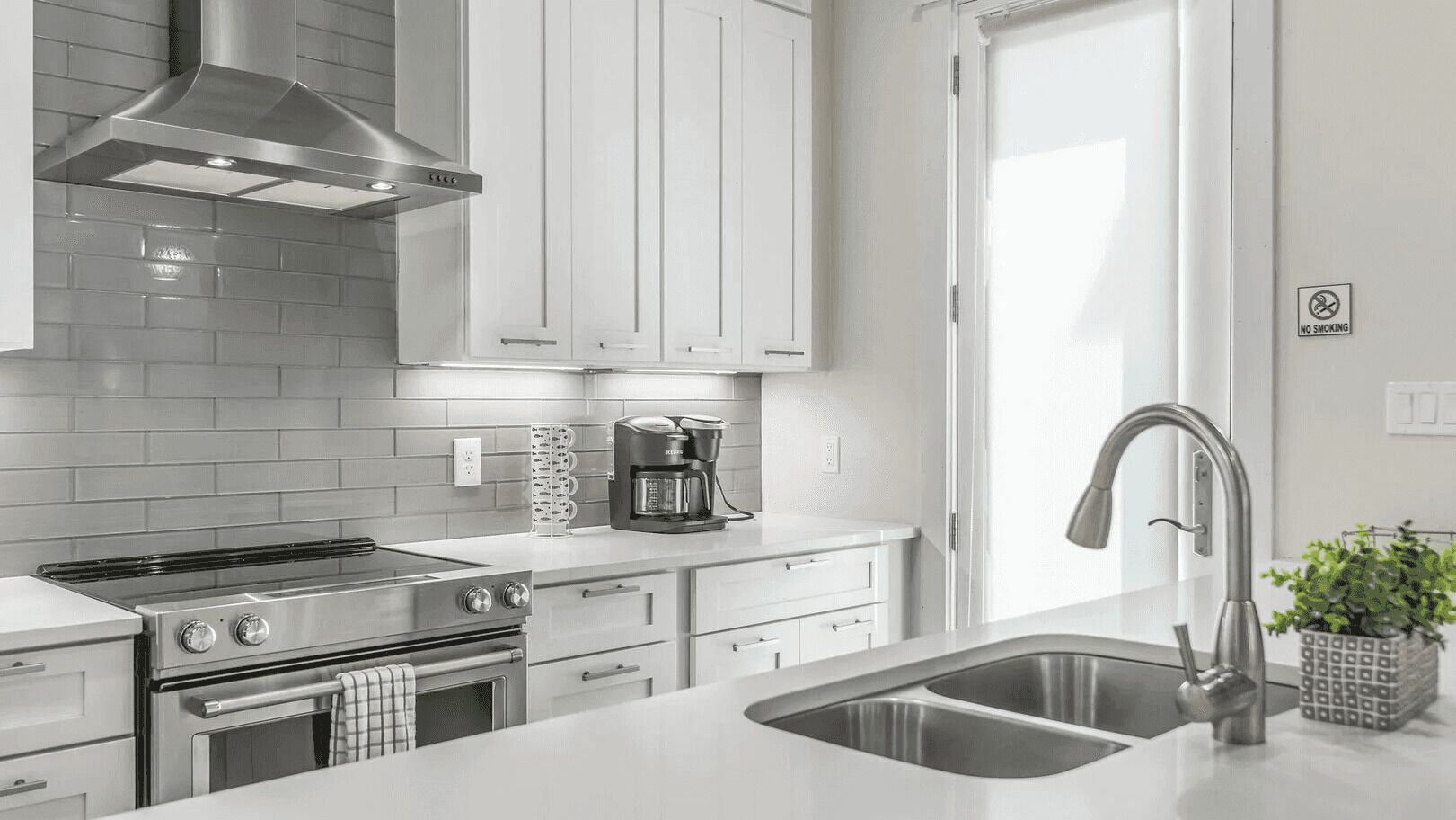 A modern kitchen with stainless steel appliances, white cabinetry, and a built-in oven.