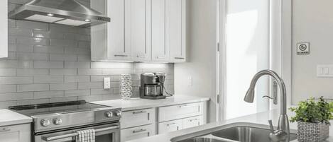 A modern kitchen with stainless steel appliances, white cabinetry, and a built-in oven.