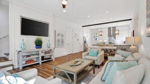 A spacious living room with a flat-screen TV, a coffee table, and a sofa with decorative pillows. - Pura Vida by Avantstay 30A Treetop Retreat Shared Pool + Private Beach Access + Bikes (Panama City Beach)