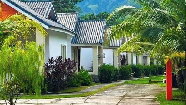 A row of traditional-style buildings with tiled roofs, surrounded by lush greenery and a stone pathway. - Dreamz Village (Langkawi)