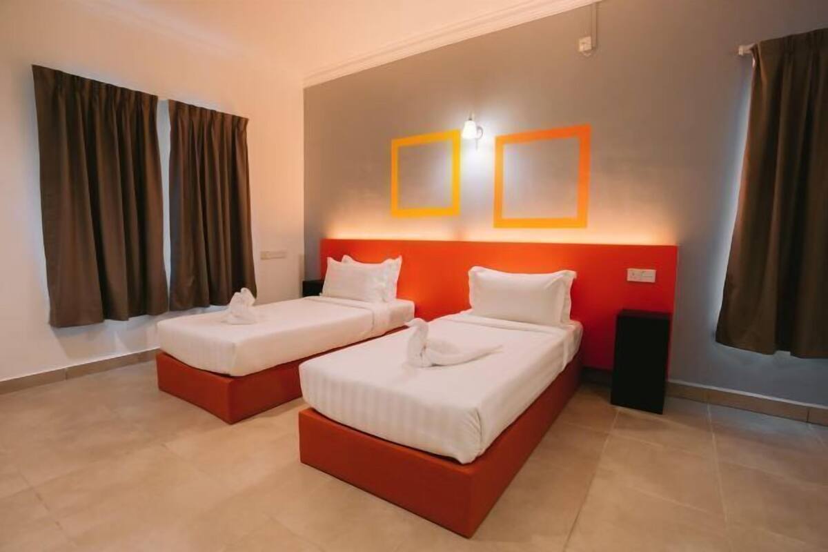 Habitación de hotel con dos camas, una pared de acento roja y un diseño moderno.