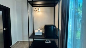 A compact room with a black metal shelf unit, a black appliance, a white towel, and a small white object on the lower shelf. - Dreamz Village (Langkawi)