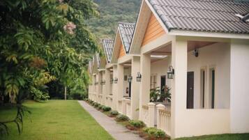 A row of white buildings with pitched roofs, each with a balcony and a small garden area.