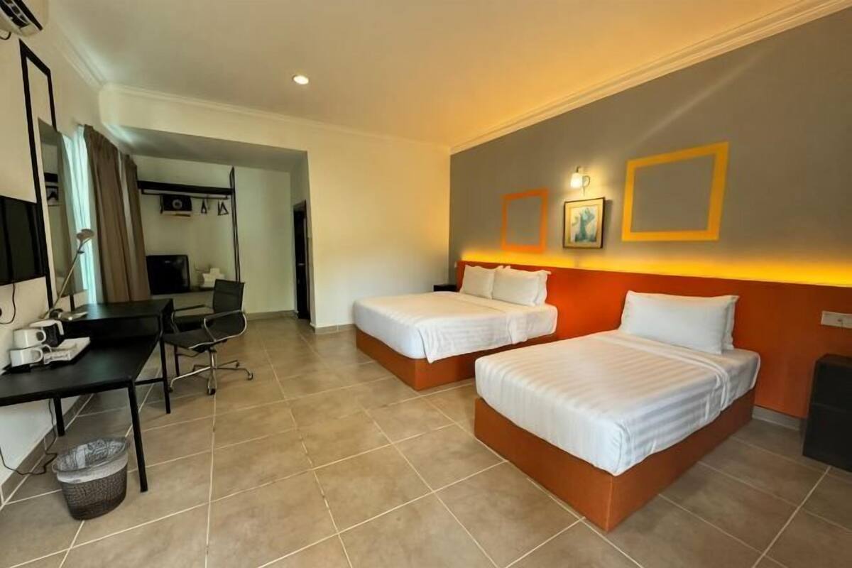 Habitación de hotel con dos camas, un escritorio, una silla, televisión y baño.