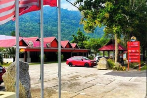 A building with a red roof, a red car parked in front, and a signboard with text.