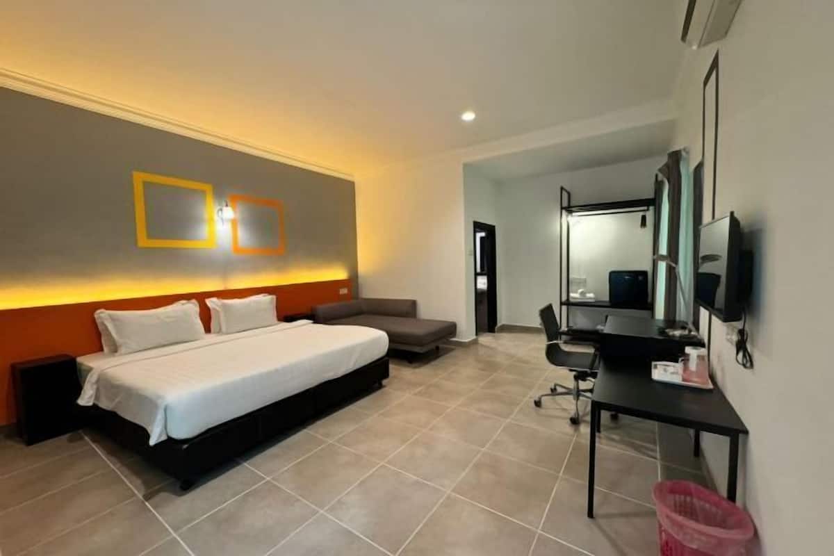 Una habitación de hotel con cama, escritorio, silla, televisor y cesto de basura.