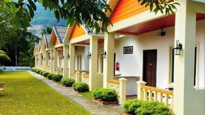 A row of hotel rooms with individual entrances, each with a small garden area and a pathway leading to the entrance. - Dreamz Village (Langkawi)