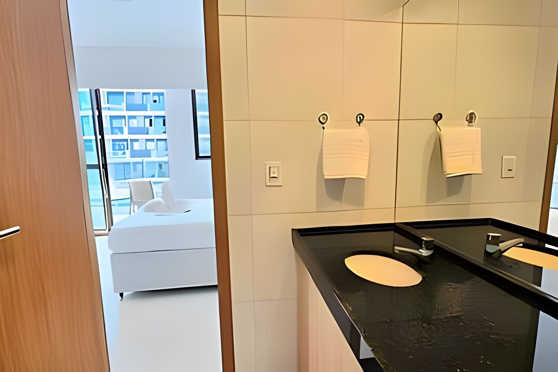 Casa de banho moderna com bancada preta, duas pias e um espelho grande.
