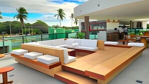 A modern outdoor lounge area with seating and a bar. - Makia Beach Experience (Ipojuca)