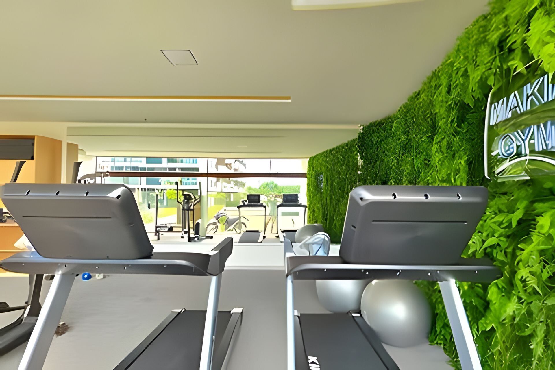 A gym with treadmills, exercise equipment, and a green wall with a sign.