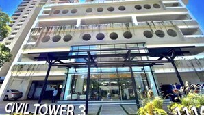 A multi-story building with a modern architectural design, featuring a prominent entrance with glass doors and a series of circular windows on the facade.