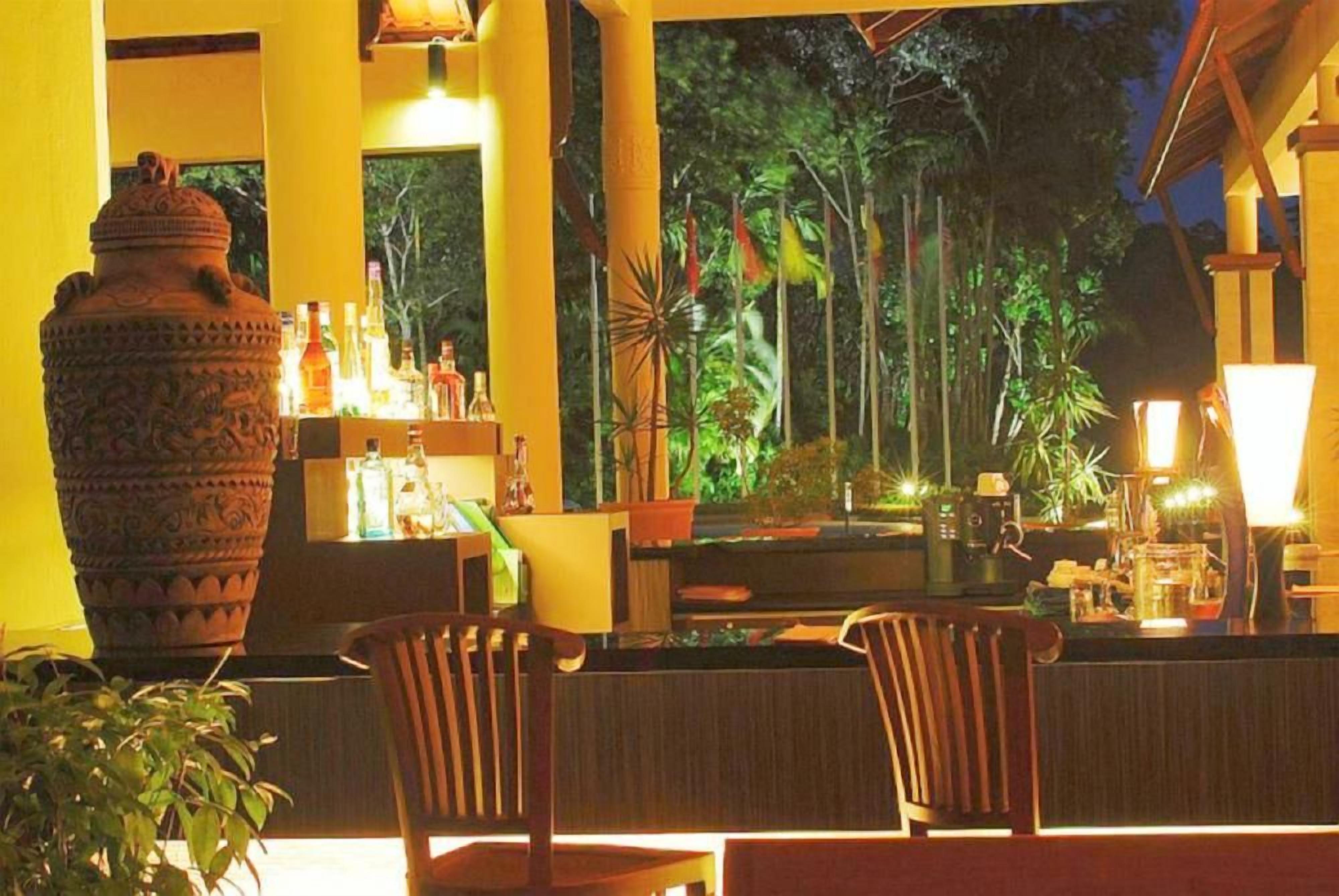 A bar area with a large decorative pot, chairs, and a view of the outdoors.