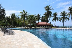 A swimming pool with lounge chairs and palm trees. - Damai Lagoon Resort (Kuching)