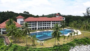 Un resort con una piscina grande, palme e un edificio con numerosi balconi.