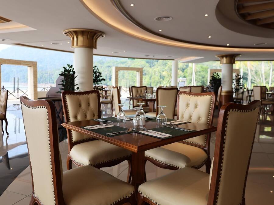 A formal dining area with a large table, upholstered chairs, and a view of the outdoors.