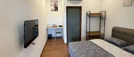 Un dormitorio con cama, escritorio, silla, televisor, literas y una puerta.
