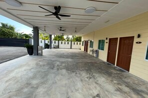 A covered outdoor area with ceiling fans, a concrete floor, and a row of doors on the right.